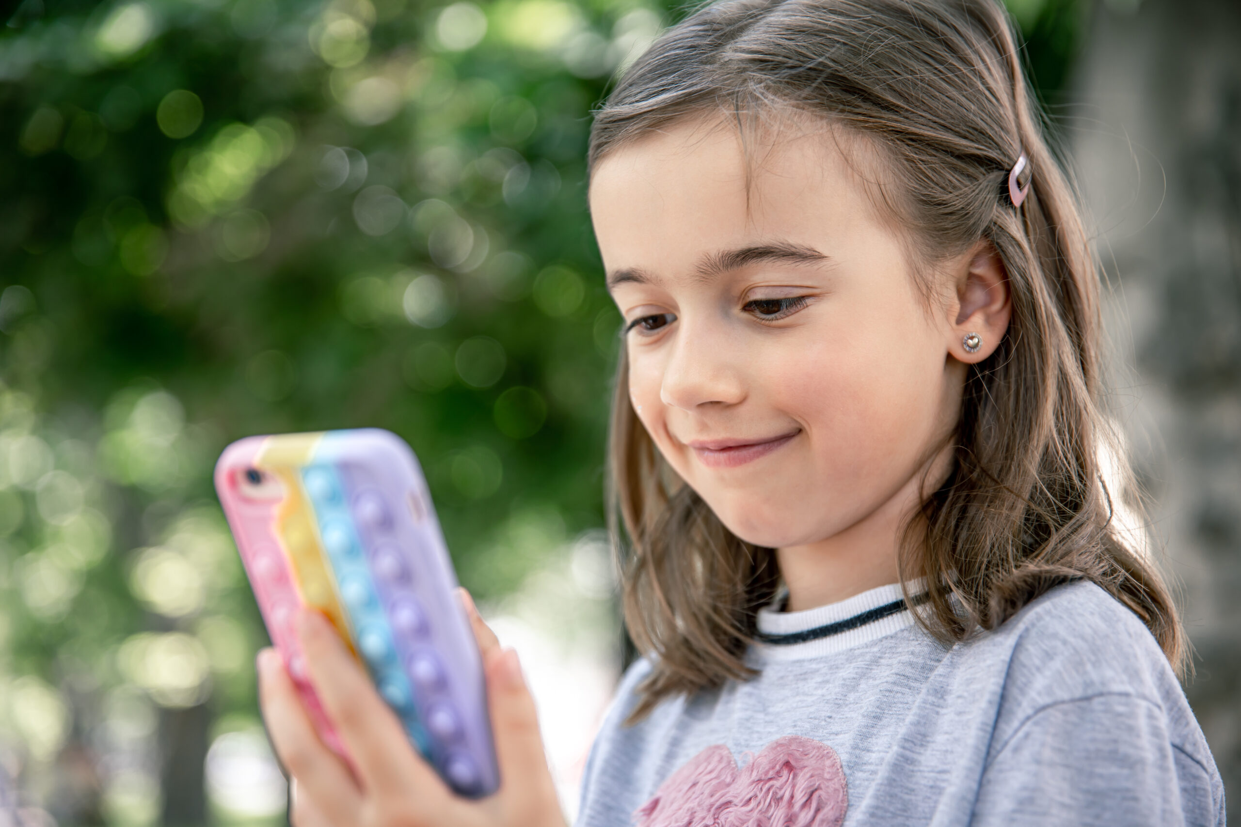 A little girl uses a phone in a trendy pop it case.